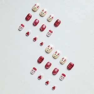 Close-up of Christmas press-on nails with reindeer, snowflake, and plaid patterns