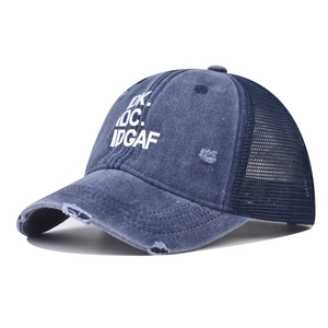 Dettaglio del cappello trucker in denim usurato con rete e slogan ricamato