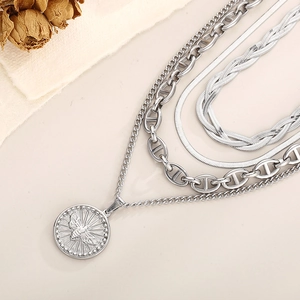 Detail of multi-layer silver necklace with bee relief coin pendant and mixed chain textures