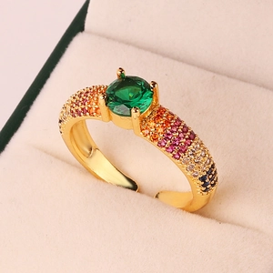 Macro shot of an adjustable gold ring featuring a green main stone and rainbow gemstones