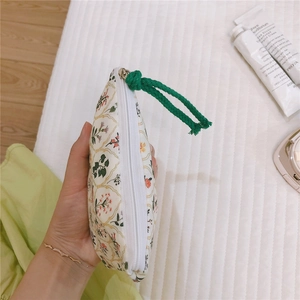 Close-up of a floral cotton mini pouch with green cord zipper pull held by a person