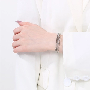 Detail of silver double-layered stainless steel bracelet on model wearing white blazer