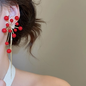 Detailed view of red pearl tassel earrings with golden starburst and rhinestone accents