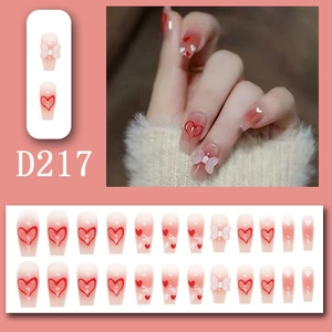 Detail of long coffin press-on nails with pink gradient, heart patterns and 3D bows