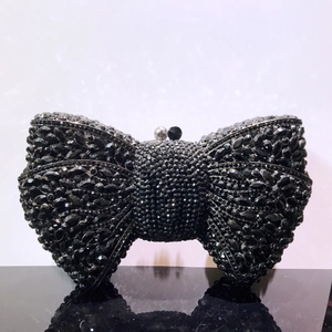 Close-up of black bow-shaped clutch bag with sparkling rhinestones and bead clasp