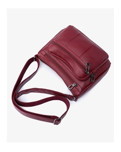 Detail of wine red crossbody bag showing pebble grain leather and three front zip pockets