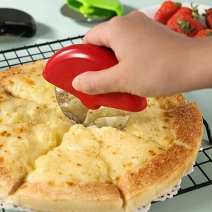 Stainless steel pizza cutter with red handle slicing through a fresh pizza