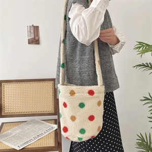 Detail of plush beige bucket bag with colorful polka dots worn by a fashion model