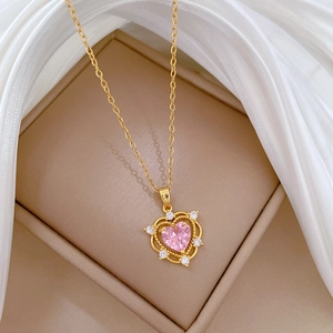 Close-up of heart-shaped gold necklace with pink stone on silk inside a gift box