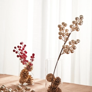 Golden and red Christmas berry branches with pine cones in a glass vase home decoration