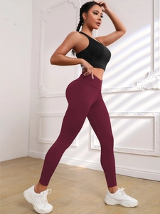 Detail of high-waist burgundy yoga pants with peach butt lifting and breathable fabric