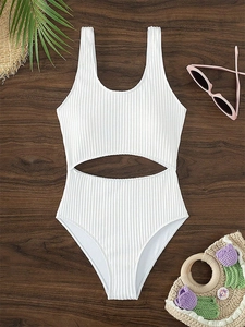 Detailed view of white ribbed one-piece swimsuit with cut-out waist on wooden background
