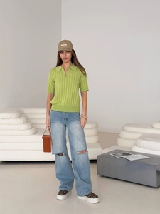Green knit zip-up polo t-shirt with ripped blue wide-leg jeans and casual accessories