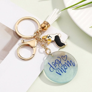 Close-up of golden dog mom keychain with teal resin pendant and white tassel detail