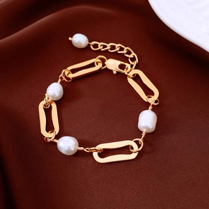 Macro shot of 18k gold plated chain bracelet with five lustrous white pearls on silk background