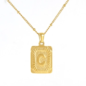 Detail of 18K gold-plated rectangle pendant with embossed letter C and sunburst texture