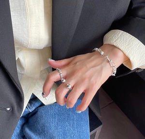 Close-up of minimalist 925 silver twist ring and chain bracelet on a hand