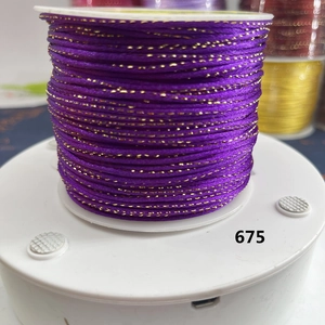 Macro detail of dark purple cord with metallic gold thread on white spool No. 675