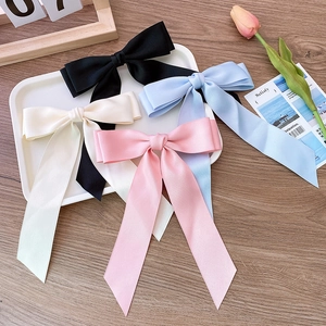 Detail view of satin ribbon bow hair clips in black, blue, cream, and pink colors