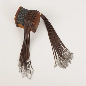 Detailed view of brown waxed necklace cords with silver lobster clasps on a small wooden box