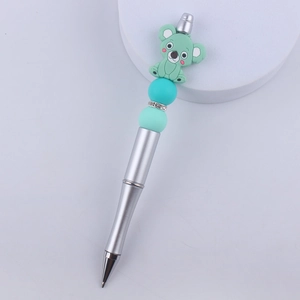 Close-up of DIY beaded pen featuring a green koala silicone charm and mint green beads