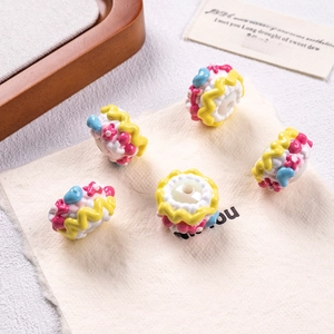Detailed view of handmade cake-shaped acrylic beads with floral and heart patterns