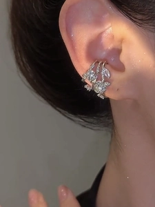 Macro view of silver triple-layer zircon flower ear cuff on ear with leaf details