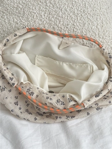 Detail view of floral canvas tote bag interior with drawstring and orange braided handle