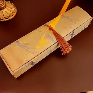 Golden vintage jewelry box with blue wave patterns and a brown tassel on leather