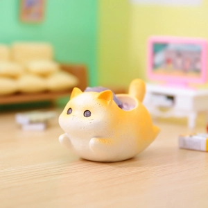 Macro shot of a yellow cat-shaped resin mini planter on a cozy miniature desk set