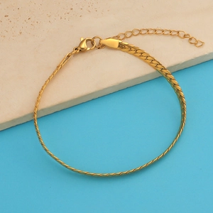 Detail of gold flat snake chain bracelet with adjustable lobster clasp on stone texture