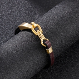 Macro shot of dark brown braided leather bracelet with matte gold buckle on stand