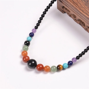 Macro shot of 6mm natural chakra stone beads on a black bohemian beaded necklace