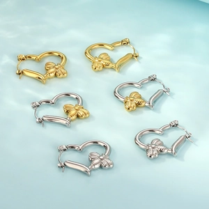 Detailed view of heart-shaped hoop earrings with 3D bee charms in gold and silver
