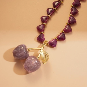 Macro detail of acrylic cherry heart pendant with purple glitter finish on beige background