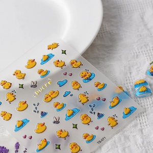 Detailansicht von 3D-Nagelstickern mit gelben Enten und blauen Wasserwellen auf weißem Teller