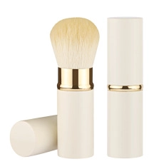 Detail of retractable makeup brush showing cream casing and golden metal ring