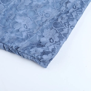 Macro shot of delicate floral lace texture on blue bodycon dress with intricate mesh embroidery