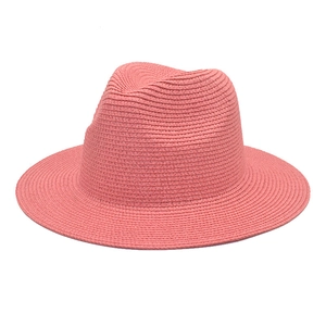 Detail of coral pink straw fedora hat showing tight weave texture and classic crown shape