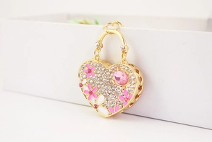 Macro shot of a heart pendant with pink floral enamel and crystals on a gold keyring