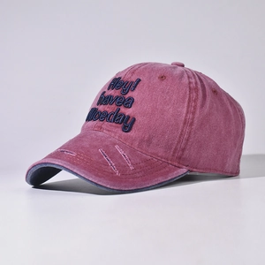 Detail einer Vintage gewaschenen weinroten Baseballkappe mit blauer Stickerei-Verzierung