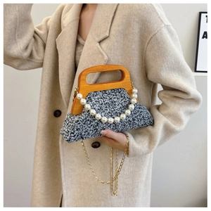Detail of tweed evening bag with wooden handle and elegant pearl chain accessory