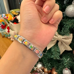 Detail of stainless steel modular charm bracelet featuring colorful cartoon enamel links