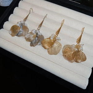 Detailed macro of hollow petal earrings with pearls on a soft beige velvet jewelry tray