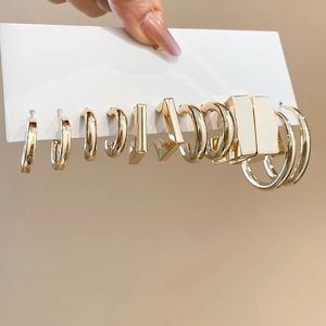 Close-up of gold geometric C-shape hoop earrings set on a white display card