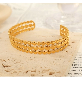 Macro view of triple-row gold beaded texture on a minimalist stainless steel open cuff bracelet