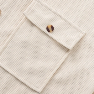 Detalle del tejido tipo gofre con bolsillo en el pecho y botón de carey beige