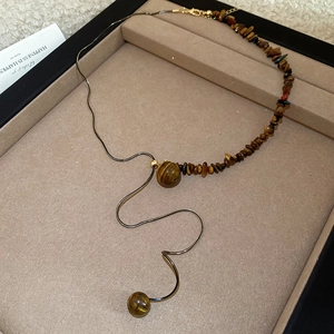 Tiger eye stone necklace with gold snake chain detail on jewelry display tray