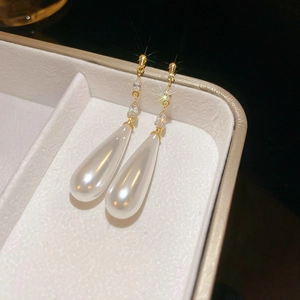 Macro shot of long waterdrop pearl earrings with gold plating and cubic zirconia