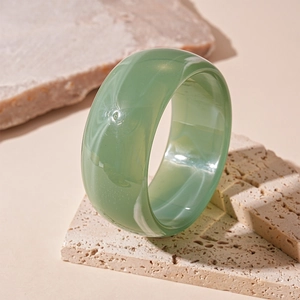 Detailed view of green marble pattern acrylic bangle on a natural stone base